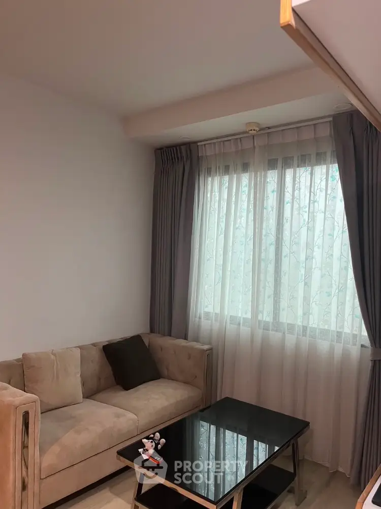 Cozy living room with elegant sofa and modern coffee table near large window with curtains.