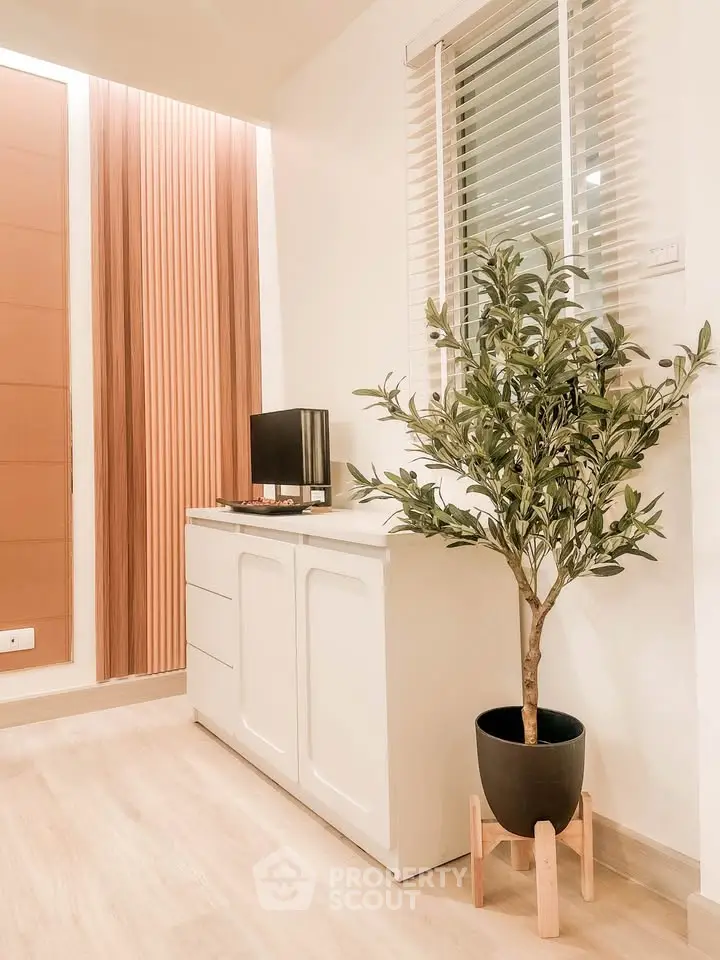 Modern interior with stylish cabinet and potted plant, featuring elegant wood paneling and natural light.