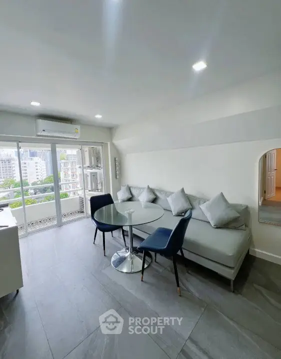 Modern living room with sleek furniture and balcony view in a high-rise apartment.
