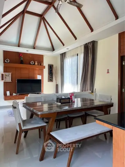 Elegant living room with vaulted ceiling and modern dining area, perfect for stylish gatherings.