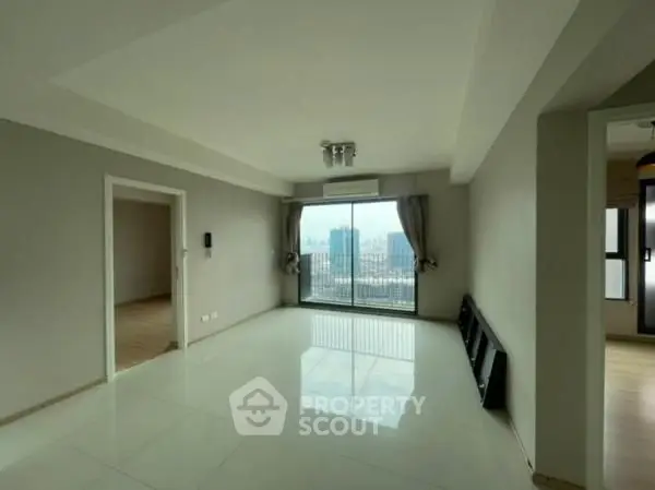 Spacious living room with large window offering stunning city view in modern apartment.
