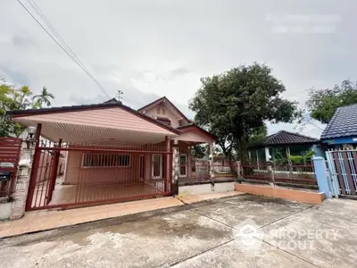 Charming single-story home with a spacious front yard and secure gated entrance, featuring a traditional design with a welcoming porch and terracotta roof tiles.