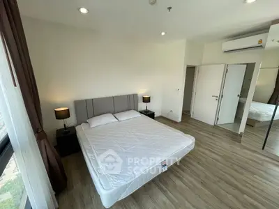 Spacious bedroom with modern decor and large windows for natural light.