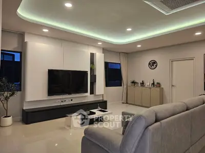 Modern living room with sleek design, featuring a large TV, stylish furniture, and ambient lighting.