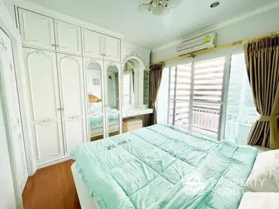 Bright bedroom with elegant white wardrobe and large window overlooking balcony.