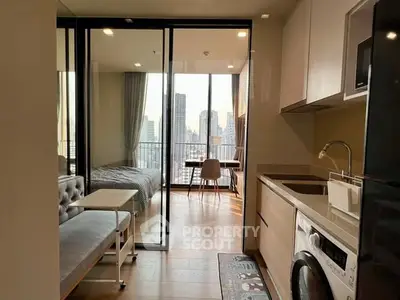Modern apartment with open kitchen and city view from balcony, featuring sleek design and natural light.