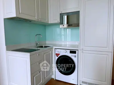 Modern kitchen with sleek cabinetry and built-in appliances, featuring a washing machine and glass backsplash.