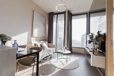 Modern living room with large windows and stylish decor in a high-rise apartment.