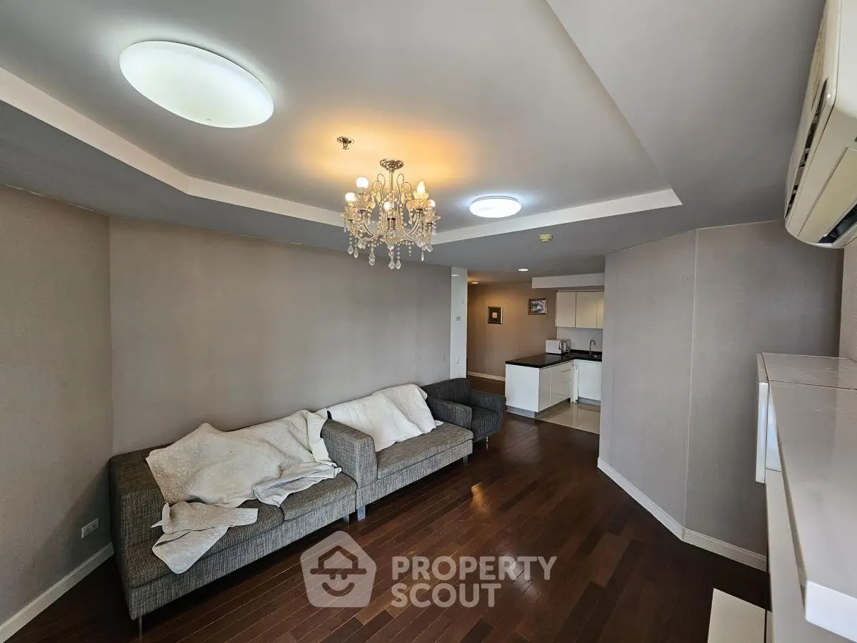 Spacious living room with elegant chandelier and modern open kitchen layout.