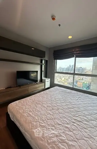 Spacious bedroom with city view and modern furnishings in high-rise apartment.
