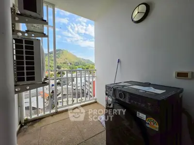 Charming balcony with scenic view and modern washing machine in urban setting.