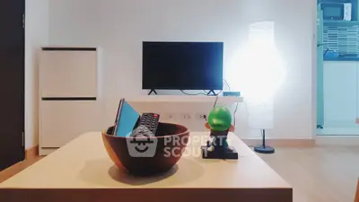 Modern living room with TV, stylish decor, and open kitchen view.