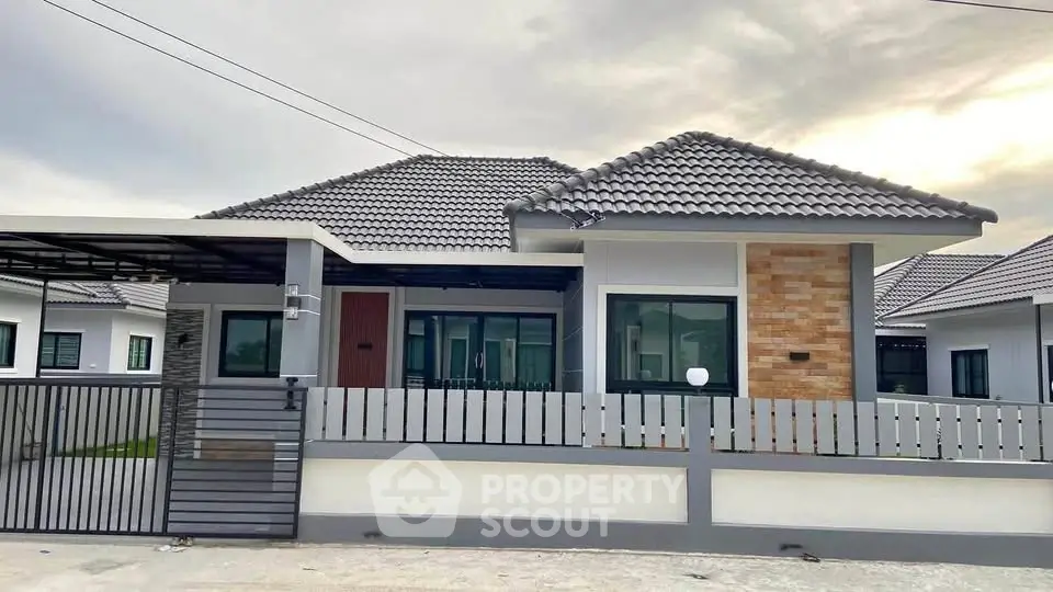 Modern single-story house with tiled roof and gated entrance in suburban neighborhood.