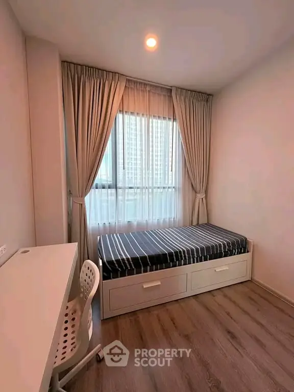 Cozy bedroom with single bed, study desk, and large window with city view.