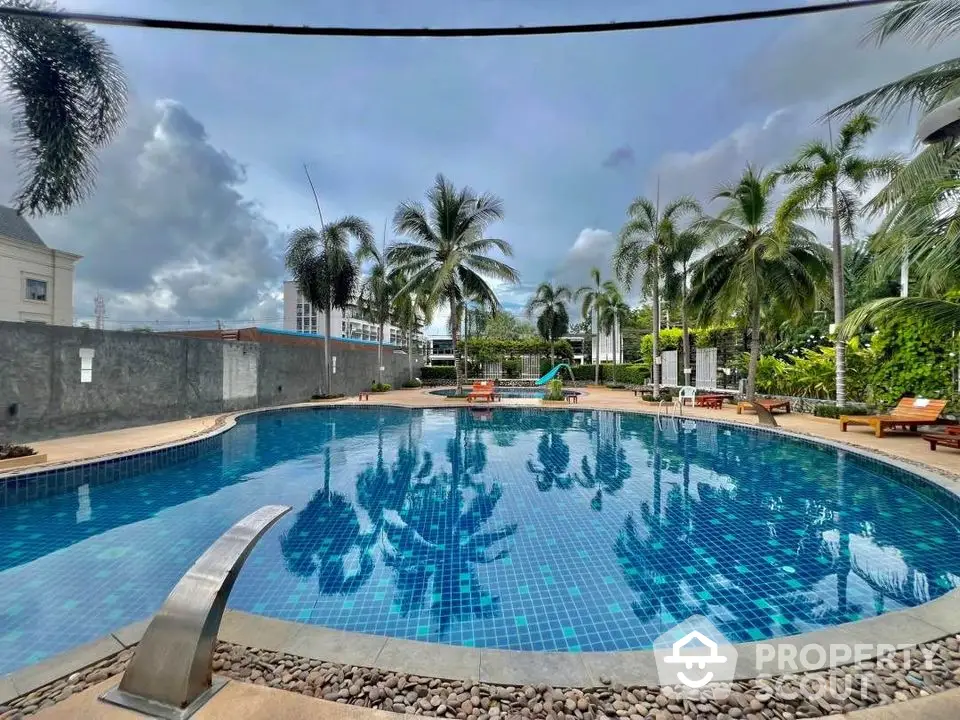 Luxurious residential pool surrounded by palm trees and lounge chairs, perfect for relaxation.