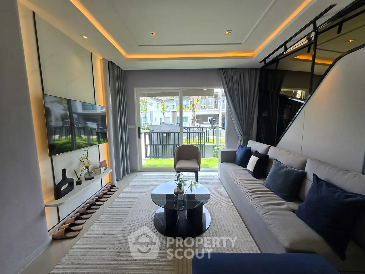 Modern living room with stylish decor and large windows offering natural light and garden view.