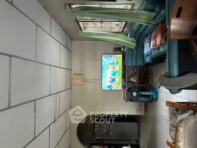 Cozy living room with tiled floor, comfortable seating, and wall-mounted TV, perfect for relaxation.
