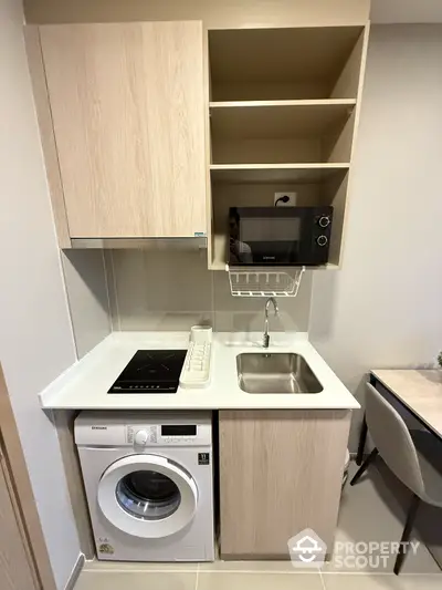 Compact modern kitchen with washing machine and microwave in stylish apartment