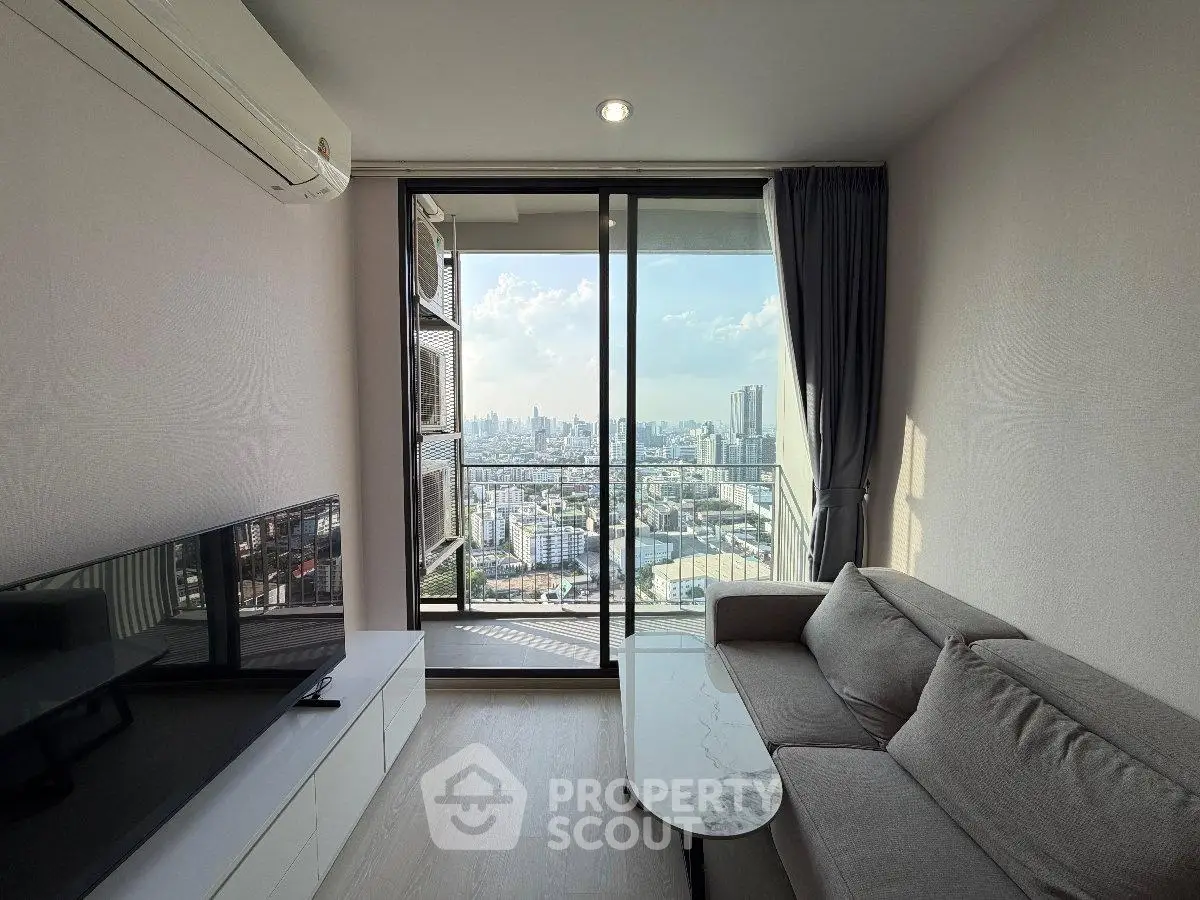 Modern living room with city view, featuring sleek furniture and large windows for natural light.