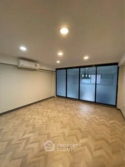 Spacious living room with modern lighting and large frosted glass doors.