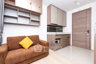Modern compact living room with cozy brown sofa and sleek kitchen area.