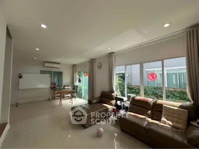 Spacious living room with modern leather sofas and large windows offering natural light.