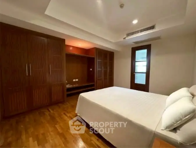Spacious bedroom with wooden flooring and built-in wardrobes