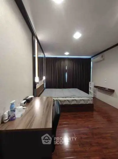 Modern bedroom with wooden flooring and minimalist design, featuring a sleek desk and comfortable bed.