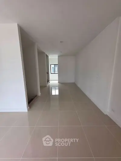 Spacious modern living area with sleek tile flooring and ample natural light.