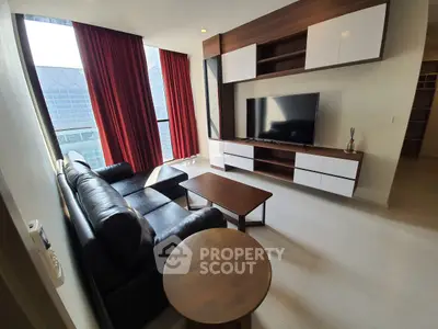 Modern living room with sleek furniture and large TV, featuring floor-to-ceiling windows and stylish red curtains.