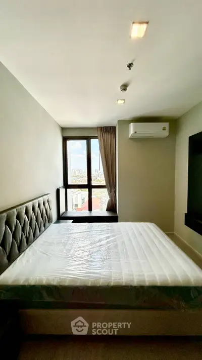 Modern bedroom with large window and air conditioning in high-rise apartment