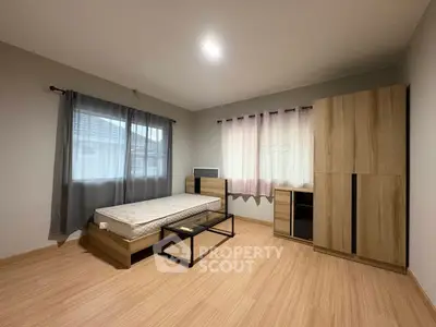 Spacious bedroom with modern wooden furniture and large windows for natural light.