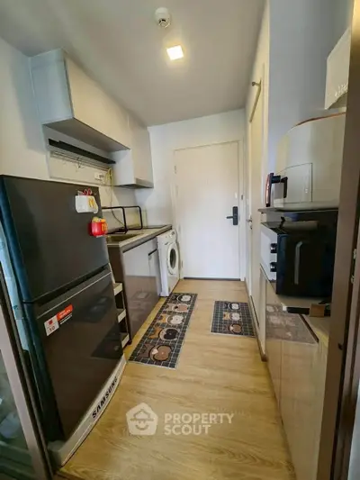 Modern kitchen with appliances including fridge, washing machine, and microwave in compact layout.