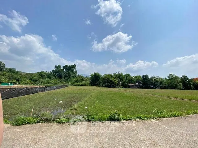 Expansive green land plot under clear blue sky, perfect for development opportunities.