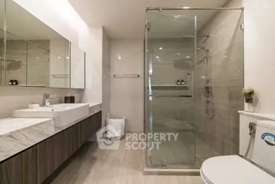 Modern bathroom with glass shower, sleek vanity, and elegant fixtures.