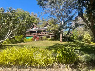 Charming rustic house surrounded by lush greenery and mature trees, offering serene and picturesque views.