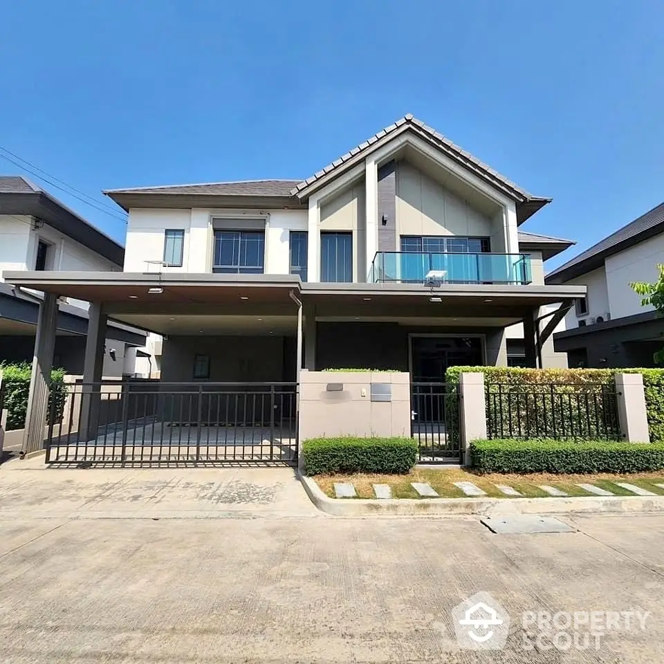 Modern two-story house with balcony and spacious driveway in a serene neighborhood.