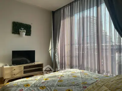 Cozy bedroom with large window and TV, offering a bright and inviting atmosphere.