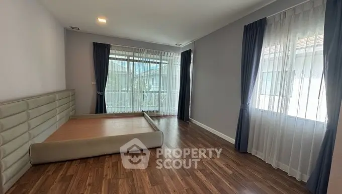 Spacious bedroom with large windows and wooden flooring