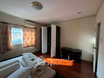 Spacious bedroom with wooden flooring and ample natural light