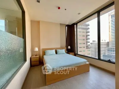 Spacious bedroom with large windows offering stunning city views in modern apartment.