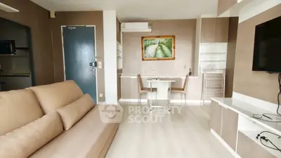 Modern living room with beige sofa, wall art, and dining area in open layout apartment.