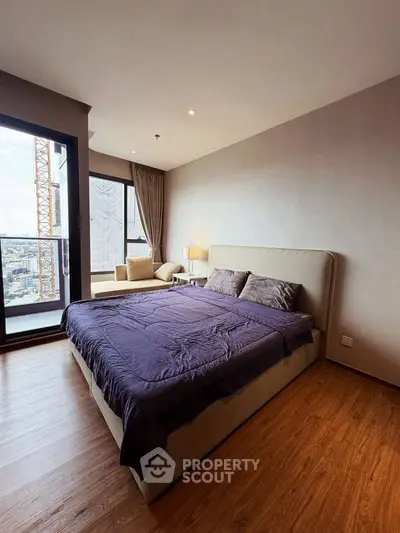 Spacious bedroom with city view and modern furnishings in a high-rise apartment.