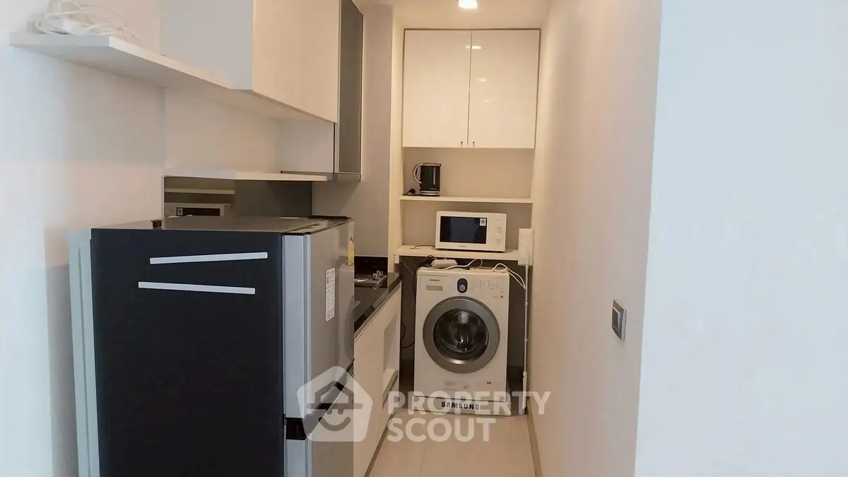 Compact kitchen with modern appliances including washing machine and microwave.