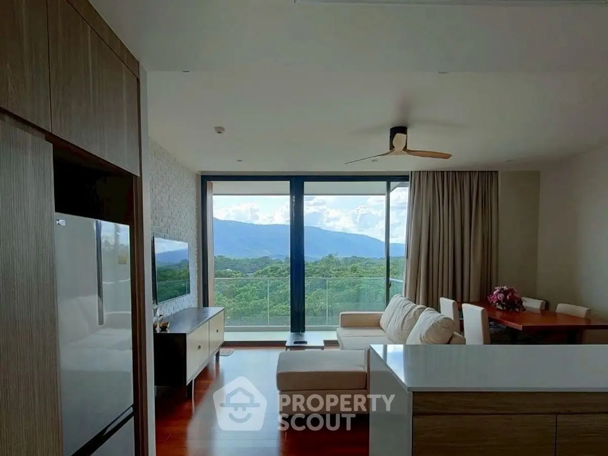 Modern living room with stunning mountain view and spacious balcony access.