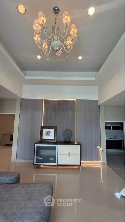 Elegant living room with chandelier and modern decor, featuring a stylish cabinet and cozy seating area.