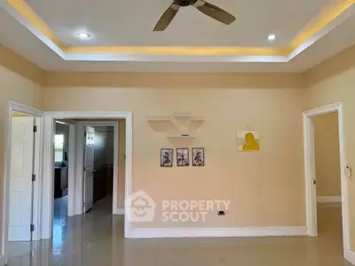 Spacious living room with modern ceiling fan and recessed lighting, featuring elegant wall decor and glossy tiled flooring.