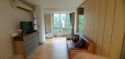 Spacious living room with modern decor and large windows offering a serene view of greenery.