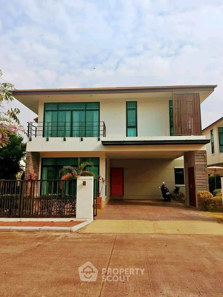 Modern two-story house with large windows and a spacious driveway.
