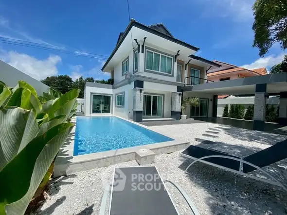 Luxurious modern villa with private pool and spacious outdoor area under clear blue sky.